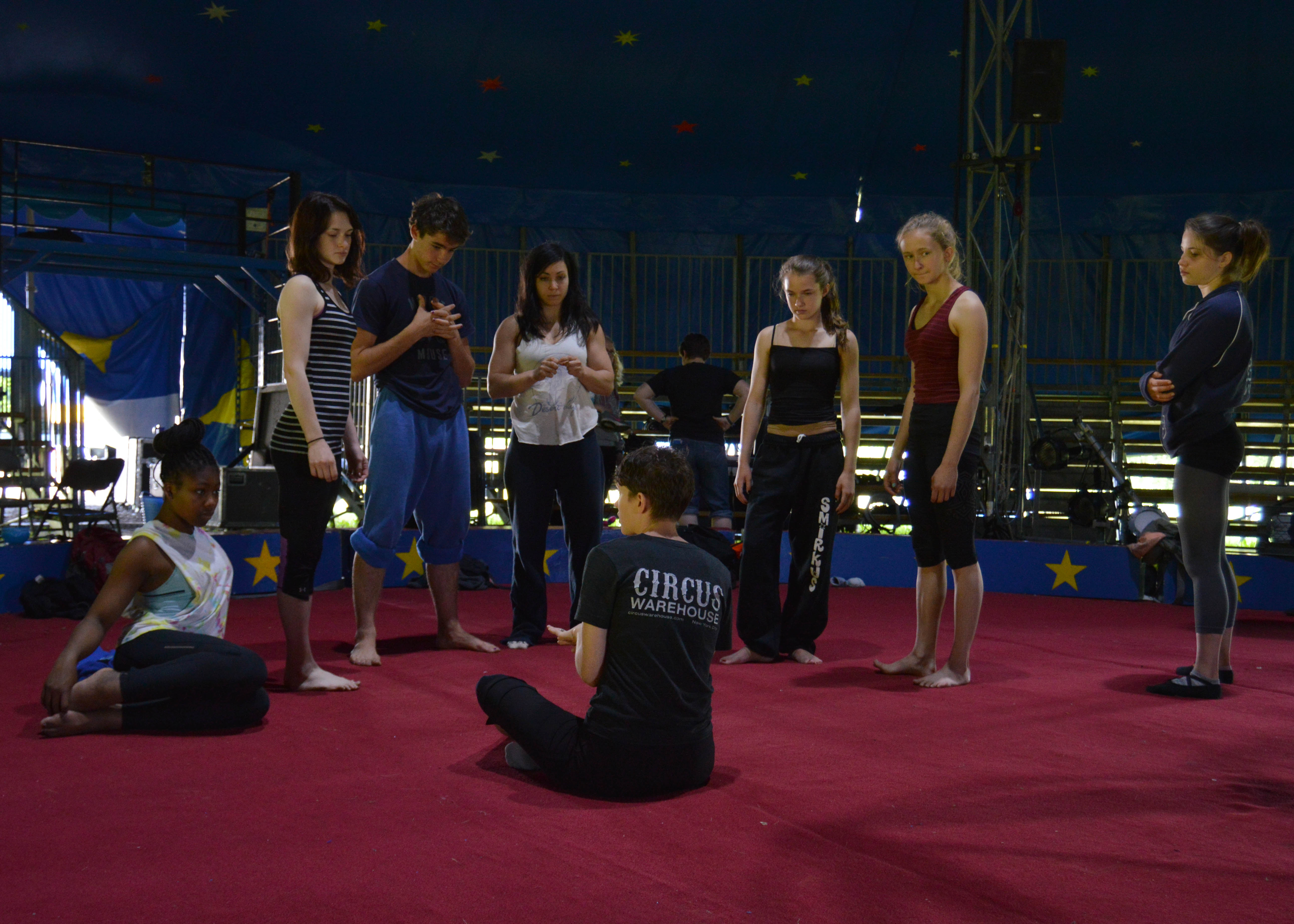 Troupers gather around 2015 Circus Smirkus Aerial Coach Alisan Funk as she gives feed back.