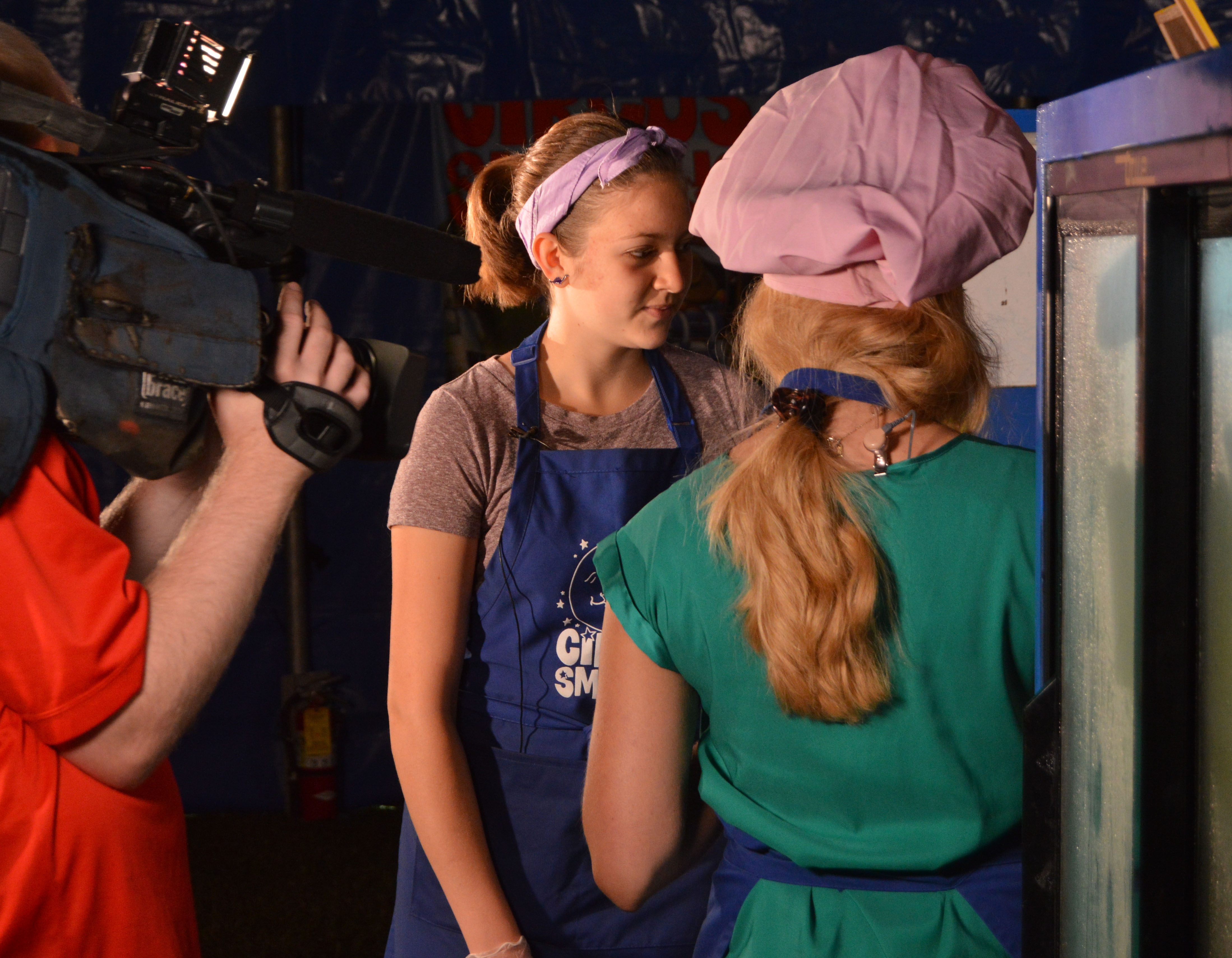 Alaina Pinto leans how to spin cotton candy from concessionaire Becky Scheff.